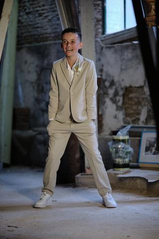 Jongbruidegom in beige pak met bloem straalt in industrieel interieur Torpedoloods Schiedam, trouwreportage - Trouwshoot Stef