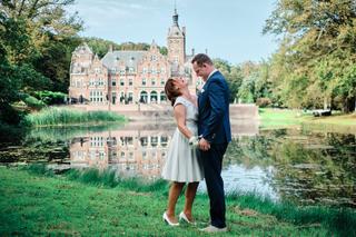 Nick en Mirjam kijken elkaar verliefd aan aan het water van Duin & Kruidberg, kasteel weerspiegeld achter hen - Trouwshoot St