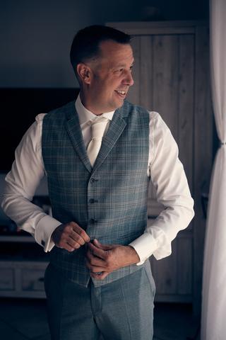 Bruidegom Michiel in grijs geruite gilet en wit overhemd, trouwreportage Fort Beemster Heemskerk - Trouwshoot Stefan Segers
