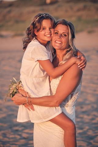 Bruid Jolanda en dochter Lisa omhelzen elkaar op het strand bij Scheveningen, trouwreportage Strandclub Naturel - Trouwshoot