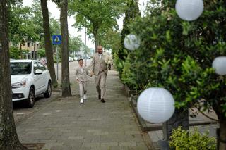 Bruidspaar loopt hand in hand door groene straat in Schiedam, trouwreportage bij Sodafabriek - Trouwshoot Stefan Segers