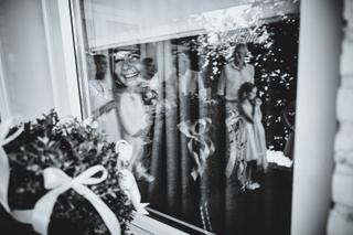Bruid Vanessa kijkt lachend door raam met confetti, trouwreportage Manuel Scheveningen - Trouwshoot Stefan Segers