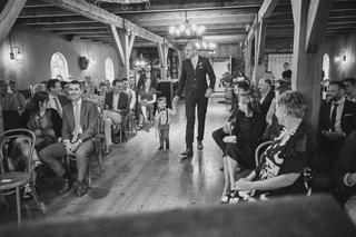 Bruidegom Robbert loopt door de feestzaal onder het houten balkenplafond van Boerderij Burgersdijk, gasten volgen zijn bewegi
