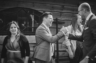 Ilse en Robbert lachen voluit met gasten op Boerderij Burgersdijk. Warme momentopname van pure blijdschap tijdens hun bruilof
