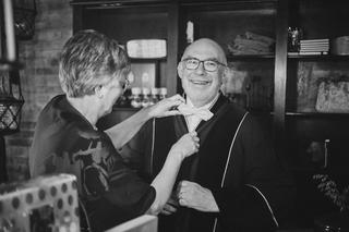 Bruidegom Robbert krijgt zijn stropdas gestrikt door een gast op Boerderij Burgersdijk - Trouwshoot Stefan Segers