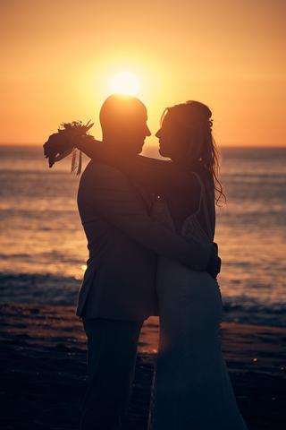 Bruidspaar Chris en Gerco silhouet tegen zonsondergang op strand, romantische trouwreportage Scheveningen - Trouwshoot Stefan