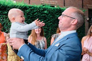 Bruidegom Johan speelt blij met kleine jongen op trouwreportage Vlietzigt Rijswijk, gasten kijken toe - Trouwshoot Stefan Seg