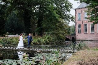 Bruidspaar Saskia en Pim op decoratieve brug bij kasteel De Knip Voorschoten, trouwreportage met water en groen - Trouwshoot