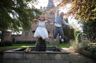 Bruidspaar Finley en Carlo springen speels in fontein bij Kasteel Sypesteyn, herfstse trouwfoto - Trouwshoot Stefan Segers