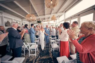 Bruidspaar Silvia en Patrick loopt door gaanderij met applaudisserende gasten, trouwreportage Beachhouse Kijkduin Den Haag -