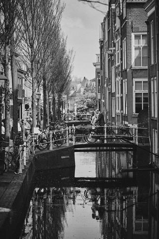 Bruidspaar Ilse en Robbert op brug over Delflandse gracht in De Lier, zwart-wit trouwreportage Boerderij Burgersdijk - Trouws