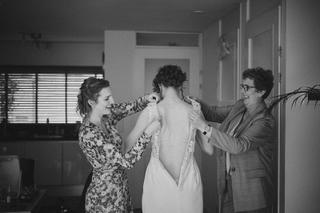 Bruid Ilse krijgt hulp met trouwjurk van twee vrouwen, getting ready moment op Boerderij Burgersdijk in De Lier - Trouwshoot