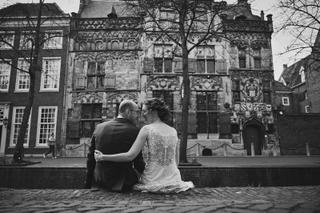 Bruidspaar Ilse en Robbert zittend op straatsteenwerk voor historisch pand, trouwreportage Boerderij Burgersdijk De Lier - Tr