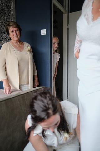 Bruid in witte jurk met bruidsmeisjes en moeder, emotioneel moment voor ceremonie Sodafabriek Schiedam, trouwreportage - Trou