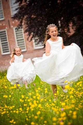 Bruidsmeisjes Lowa en Monique spelen lachend in bloemenveld, trouwreportage kasteel Duivenvoorde Voorschoten - Trouwshoot Ste