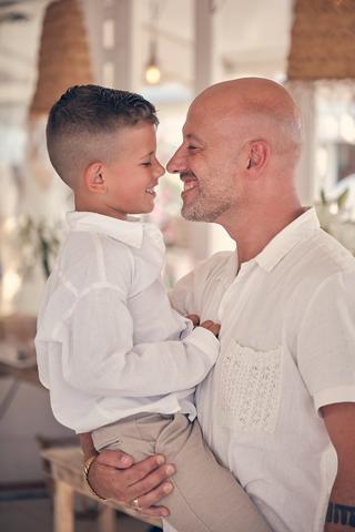 Vader Gerco met zoontje Hudson lachen elkaar aan, innig trouwmoment, strandclub Scheveningen - Trouwshoot Stefan Segers