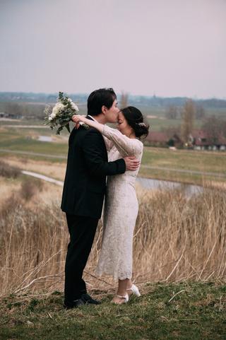 Verliefd bruidspaar omhelst elkaar in landelijk veld bij Zoetermeer, loveshoot met bruidboeket — Trouwshoot Stefan Seger