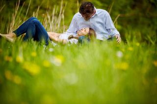 Verliefd stel ligt in groen veld met bloemen in Zoetermeer, romantische loveshoot — Trouwshoot Stefan Segers