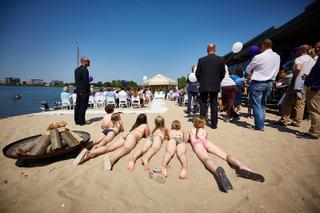 Kinderen spelen op het strand tijdens bruidsfotografie aan het water, trouwceremonie met gasten en paarse ballonnen - Trouwsh