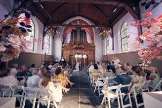 Bruidspaar Bram en Elles wisselt trouwgeloften in kerk Het Dikke Torentje, gasten kijken toe bij ceremonie met bloemenversier