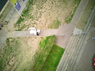 Bruidspaar onder witte paraplu op bakstenen pad in Venlo, luchtfoto - Trouwshoot Stefan Segers