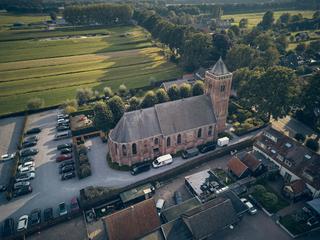 Luchtfoto van de pittoreske kerk Het Dikke Torentje omringd door landelijke weilanden en parkeerplaats - Trouwshoot Stefan Se