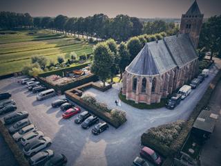 Luchtfoto bruidspaar Bram en Elles bij Het Dikke Torentje, trouwreportage ceremonie buiten kerk - Trouwshoot Stefan Segers