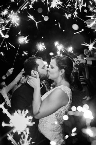 Bruidspaar kust elkaar omringd door sparklers, feestelijke avondreportage met gasten - Trouwshoot Stefan Segers