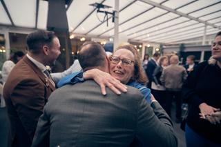 Tijdens de bruiloft van Jeroen en Martijn bij Fletcher Hotel Wipselberg: een gast omhelst de bruidegom hartelijk onder het gl
