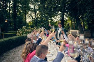 Bruidegom uit toost met gasten aan lange feesttafel onder eeuwenoude bomen op Kasteel Wijnenburg - Trouwshoot Stefan Segers