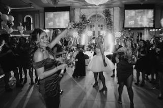 Bruiloftsgasten dansen enthousiast op trouwfeest, bruidsmeisje met bruidsboeket in spotlight, festive trouwreportage - Trouws