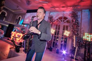 Saxofonist speelt tijdens bruidsfestijn met roze en blauwe verlichting, feestelijke trouwreportage - Trouwshoot Stefan Segers