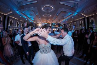 Bruidspaar danst samen op bruidsfeest in elegant verlichte zaal, gasten juichen toe, romantische trouwreportage - Trouwshoot