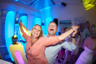 Bruidspaar dansen vrolijk op trouwfeest met blauwe neonverlichting, feestelijke bruiloftsreportage - Trouwshoot Stefan Segers