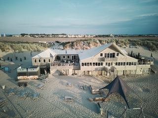 Mirjam en Jorg op het strand bij Strandpaviljoen Brouw in Ouddorp, met uitzicht op de zee en duinen - Trouwshoot Stefan Seger