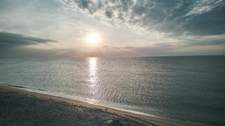 Mirjam en Jorg bij zonsondergang aan het strand van Strandpaviljoen Brouw in Ouddorp, gouden licht over rustig water - Trouws