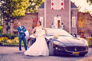 Bruidspaar poseert bij luxe auto voor historisch kasteel, bruidsboeket en bruidsjurk - Trouwshoot Stefan Segers