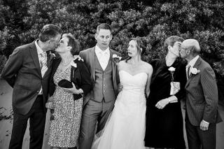Bruidspaar en familieleden lachen samen voor begroeid achtergrond, blijde trouwreportage moment - Trouwshoot Stefan Segers