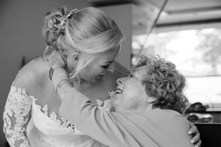 Bruid in kant trouwjurk omhelst moeder, emotioneel moment trouwreportage, zwartwit bruidsfotografie - Trouwshoot Stefan Seger