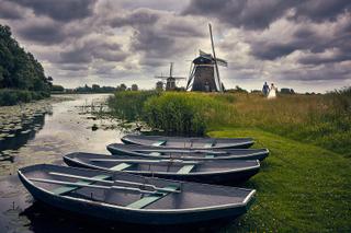Bruidspaar wandelt langs authentieke molens en boten in Nederlands landschap, romantische trouwreportage - Trouwshoot Stefan