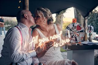 Bruidspaar Bram en Elles kussen elkaar bij neonlicht All you need is love, trouwreportage Het Dikke Torentje - Trouwshoot Ste