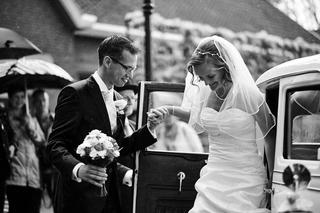 Bruid en bruidegom wisselen ringen uit bij vintage auto in de regen, innig moment vol emotie - Trouwshoot Stefan Segers