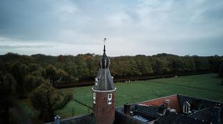 Karakteristieke Nederlandse landschapsfoto met historische toren en weiden onder bewolkte hemel - Trouwshoot Stefan Segers