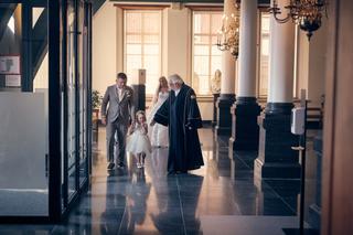 Bruidegom en bruidsmeisje volgen de ceremonie in de elegante kapel met gouden kroonluchter en zuilen - Trouwshoot Stefan Sege