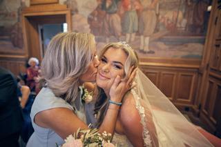 Bruid Jacky en moeder omhelzen elkaar in kerk, emotioneel moment trouwceremonie Wantij Paviljoen Dortrecht - Trouwshoot Stefa