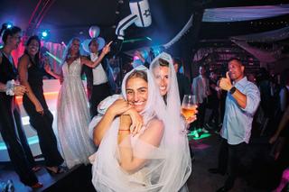 Bruidspaar Liad en Wilfried danst op feestelijk Joodse bruiloft met gasten in neon-verlichte zaal The Boathouse Kralingen, tr