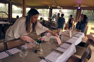 Bruid controleert tafeldecoratie met roze bloemen en menukaarten in elegant paviljoen - Trouwshoot Stefan Segers