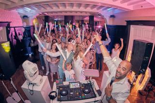 Bruidspaar Dennis en Kim in volle feestsfeer met gasten, dj aan decks met roze verlichting - Trouwshoot Stefan Segers
