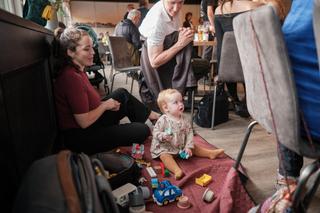 Peuter speelt met speelgoed op de vloer terwijl volwassenen rond het jubileumfeest samenkomen in Wantijpaviljoen - Trouwshoot
