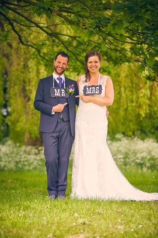 Gelukkig bruidspaar met MR en MRS-bordjes in groen park Land van Belofte Moerkapelle, trouwreportage - Trouwshoot Stefan Sege